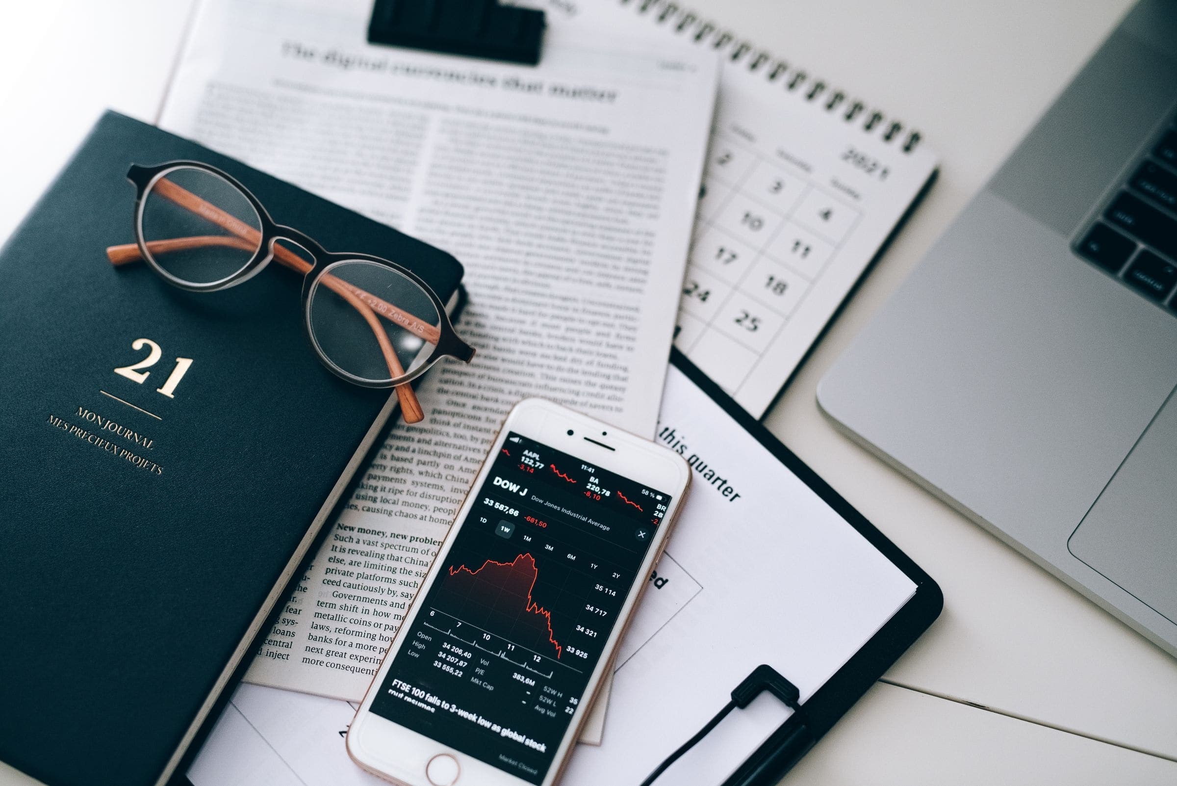 Reading glasses and financial documents on a desk.