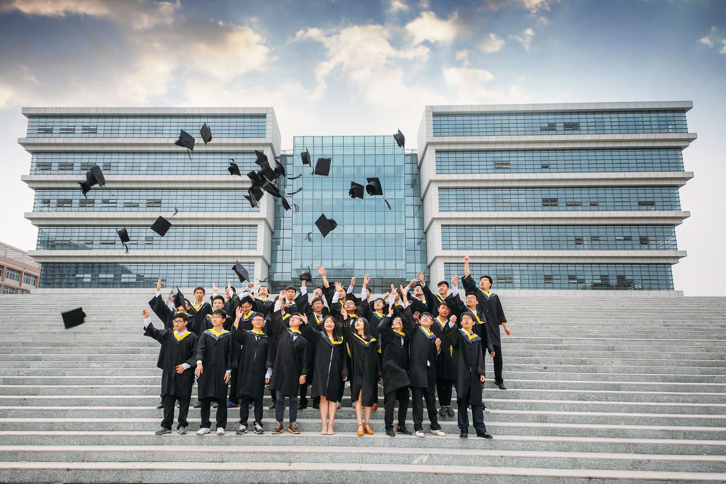 Graduates throwing their caps in celebration outside a university building.